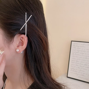 Detailed close-up of a sparkling X-shaped rhinestone hair clip worn by a model