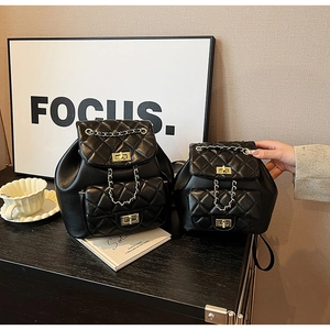 Détail de sacs à dos matelassés noirs avec chaînes dorées et fermoirs rotatifs