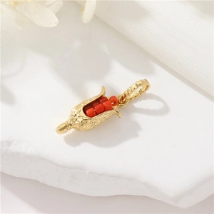 14K gold plated corn shaped pendant with red center bead on white stone texture