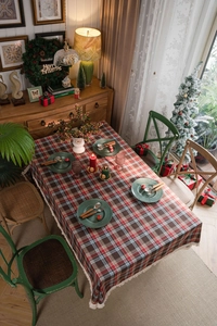 Dettaglio tovaglia a scacchi rossa e verde con nappe e decorazioni natalizie festive