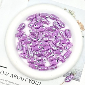 Macro detail of glossy purple fish-shaped ceramic beads for DIY jewelry making