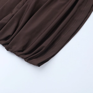 Detail of dark brown knit dress featuring ruched hemline and precise stitching quality