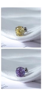 Macro shot of 4-prong round-cut zircon studs in yellow and purple titanium steel settings