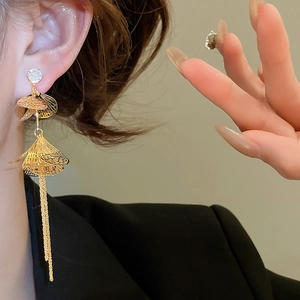 Détail macro de boucles d'oreilles pendantes dorées avec feuilles et pierre de zircon