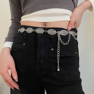 Close-up of silver concho waist chain with oval engraved metal plates on black jeans