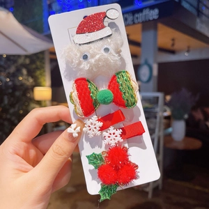 Detailed view of Christmas hair clips with plush Santa hat and glitter ribbon on a card