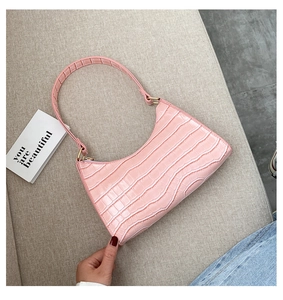 Detail of pink croc-embossed underarm bag with gold hardware and stylish shoulder strap