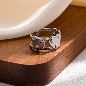 Close-up of vintage silver multi-layer hollow heart ring with rivet details on wooden stand