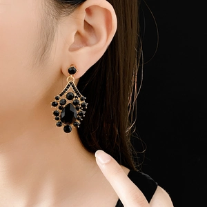 Close-up of vintage gold teardrop earrings with faceted black gemstones on model