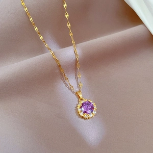Detailed close-up of a purple gemstone necklace with a gold twisted chain and zircons