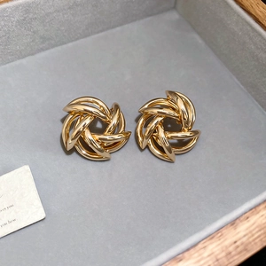 Detailed view of gold spiral swirl earrings on a premium grey velvet jewelry tray