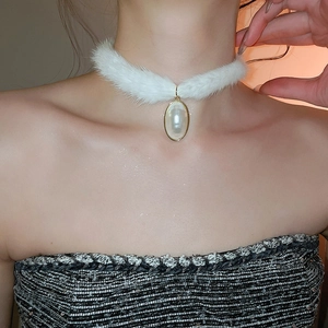 Detail of elegant white faux fur necklace with oval pearl pendant and gold metal frame