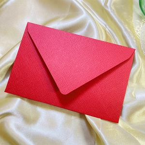 Detail of red textured paper envelope on gold silk fabric showcasing high-end paper grain