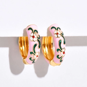Detail of pink floral enamel hoop earrings with gold finish and white flower pattern