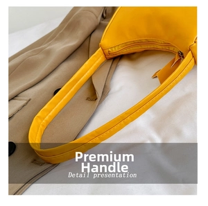 Detail view of yellow leather handbag showing fine stitching and smooth zipper closure