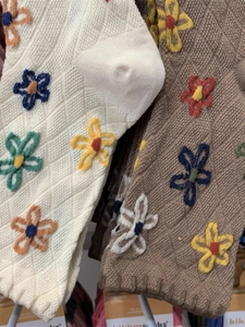 Detail of knitted crew socks with argyle pattern and 3D floral embroidery in beige and brown