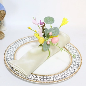 Close-up of Easter napkin ring with speckled eggs and spring flowers on a white plate