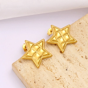 Detail of gold star earrings with diamond pattern texture and beaded edges on stone
