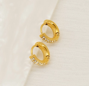 Macro detail of gold-plated titanium steel huggie earrings with clear cubic zirconia stones