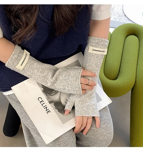 Close-up of grey knitted fingerless gloves with a white nice moment tag on wrist