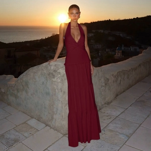 Detail of deep red V-neck maxi dress with tiered skirt and halter neck in sunset lighting
