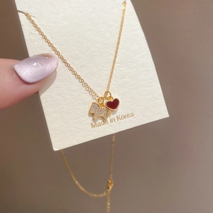 Détail du collier doré avec pendentif ours en cristal et breloque en cœur émaillé rouge