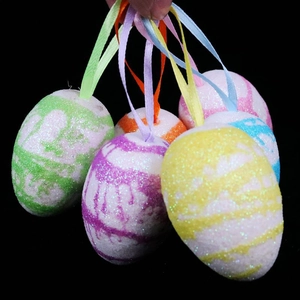 Detail of colorful glittery Easter eggs with silk ribbons held in hand for decoration