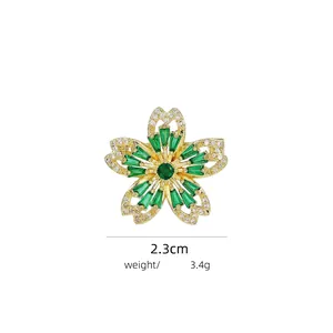 Detail of flower brooch featuring a green gemstone center and white crystal border