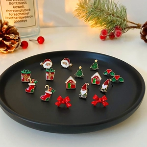 Close-up of festive Christmas earring set with Santa and tree motifs on black tray