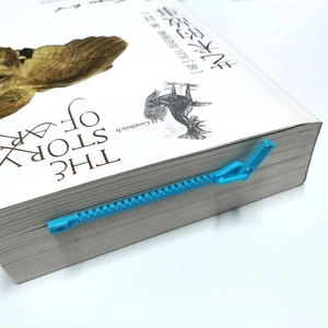 Creatieve blauwe boekenlegger in de vorm van een ritssluiting op een wit bureau geplaatst
