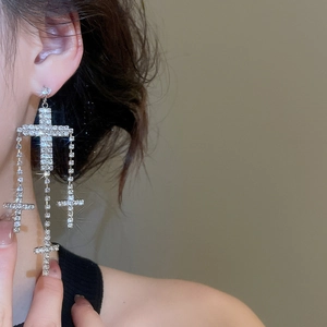 Detailed macro view of cascading silver cross tassel earrings with sparkling rhinestones