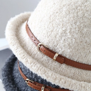 Gros plan sur chapeau bob en peluche avec boucle métallique dorée et ceinture en cuir