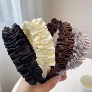 Detail showing folded fabric headbands in black, beige, brown, and grey with wave textures