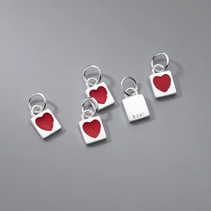 Diversi ciondoli in argento S925 con cuori in smalto rosso su sfondo grigio opaco