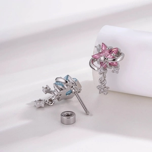 Star and moon stud earrings in silver with pink and blue pentagram pendants on white fabric