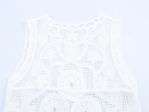 Dettaglio del gilet in maglia di pizzo bianco con motivi floreali e trama a uncinetto