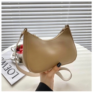 Detalle de un bolso hobo de cuero beige con herrajes dorados y correa ancha de diseño