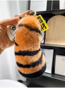 Plush tiger tail keychain with soft faux rabbit fur and golden ring displayed with car keys