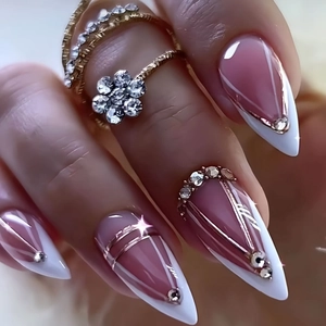 Gros plan sur de longs ongles français blancs avec strass et bague fleur dorée élégante