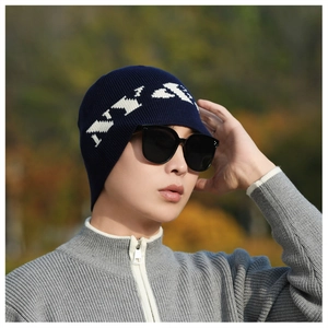 Detail of navy blue ribbed knit beanie with white patterns worn by a male model