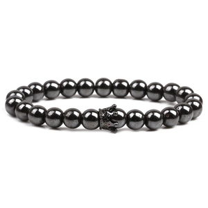 Macro detail of natural black hematite beaded bracelet featuring a vintage crown charm