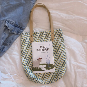 Détail du sac cabas en toile avec motifs en losange et poignées en cuir brun avec rivets