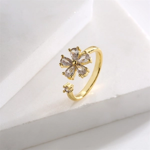 Dettaglio macro di un anello a fiore dorato regolabile con zirconi su base di marmo