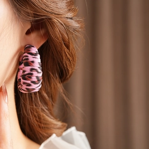 Close-up of a pink leopard print fabric-wrapped hoop earring on a model's ear