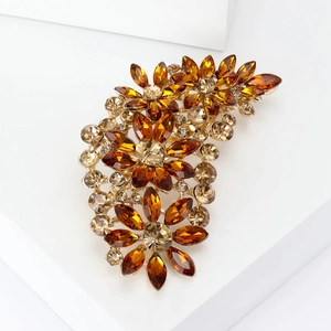 Detailed close-up of a floral brooch with amber and champagne crystals on gold metal