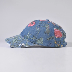 Detail of blue denim baseball cap featuring vintage floral and insect pattern embroidery