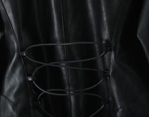 Détail de la veste en cuir noir montrant les lanières croisées et le grain du cuir