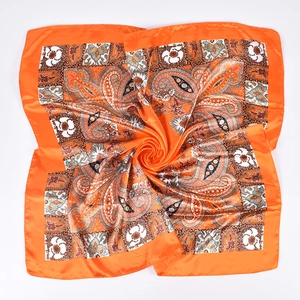 Close-up of bright orange paisley silk scarf with glossy texture and intricate patterns