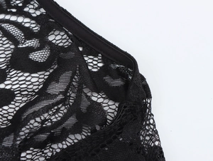 Dettaglio del tessuto in pizzo nero con motivi floreali traforati e bordi rinforzati
