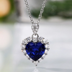 Macro shot of silver heart pendant featuring a sapphire blue stone with halo crystals